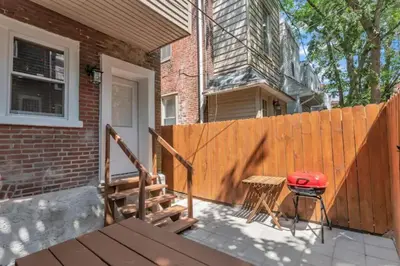 a backyard with a wooden fence and a grill at University City Executive Modern 3BR 2BA Within 5 min to Drexel, University of Pennsylvania, & Children's Hospital of Pennsylvania in Philadelphia