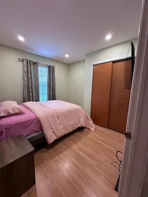 a bedroom with a pink bed and a wooden floor at Home Away From Home in Ridley Park