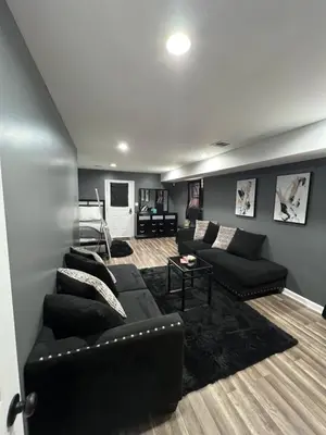 a living room with black couches and a couch at Comfortstayrus in Orange