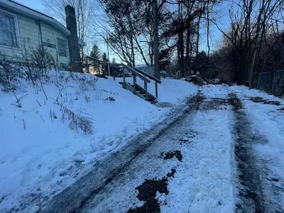 a snow covered road in front of a house at Cheerful two bedroom bungalow near Mountain Creek in West Milford