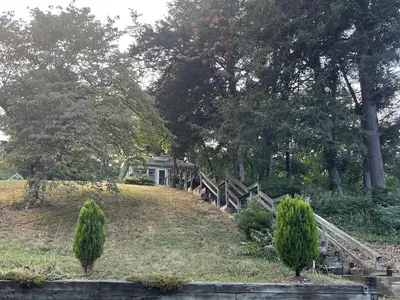a house on a hill with a fence and trees at Cheerful two bedroom bungalow near Mountain Creek in West Milford