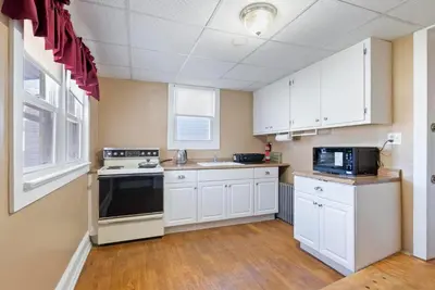 a kitchen with white cabinets and a black appliance at Candlelight Chamber - Private Room with Shared Space in Chester