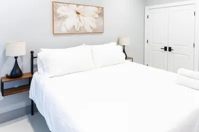 a white bedroom with a large bed with white pillows at 20 Minutes to Times Square, Stylish 2 Bedroom Apartment in West New York