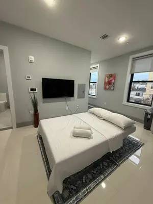 a bedroom with a large bed and a flat screen tv at 20 Minutes to Times Square, Stylish 2 Bedroom Apartment in West New York