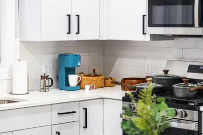 a kitchen counter with white cabinets and a blue appliance at Stylish Two Bedroom Apartment with Free Indoor Parking in West New York