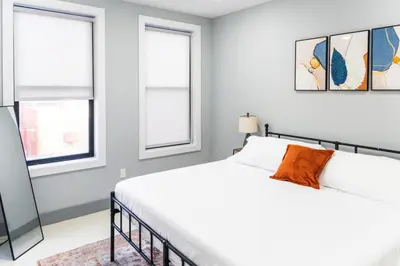 a white bedroom with a bed and two windows at Stylish Two Bedroom Apartment with Free Indoor Parking in West New York