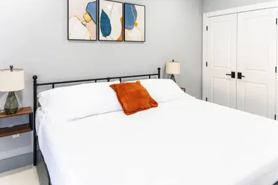 a bedroom with a white bed with an orange pillow on it at Stylish Two Bedroom Apartment with Free Indoor Parking in West New York