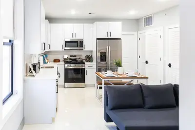 a kitchen with white cabinets and a blue couch at Stylish Two Bedroom Apartment with Free Indoor Parking in West New York