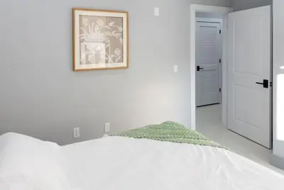 a white bedroom with a bed and a picture on the wall at 20 Minutes to Times Square with Free Indoor Parking in West New York