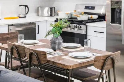 a kitchen with a wooden table with plates and flowers on it at 20 Minutes to Times Square with Free Indoor Parking in West New York