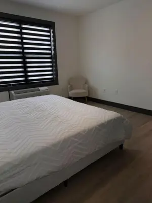 a white bedroom with a bed and a window at Spacious Apt 15 mins to NYC with Free Indoor Parking in West New York