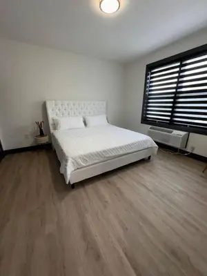 a white bedroom with a large bed and a window at Spacious Apt 15 mins to NYC with Free Indoor Parking in West New York