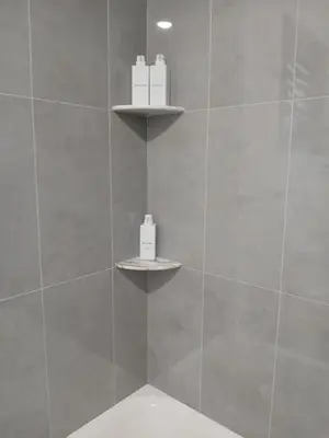 a bathroom with a shower with two shelves on the wall at Spacious Apt 15 mins to NYC with Free Indoor Parking in West New York