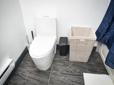 a bathroom with a white toilet and a basket at Excellent Location-20 Minutes to NYC-Free Parking in West New York