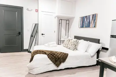 a bedroom with a white bed and a black door at Discover NYC in stylish Studio-25 mins to NYC in West New York