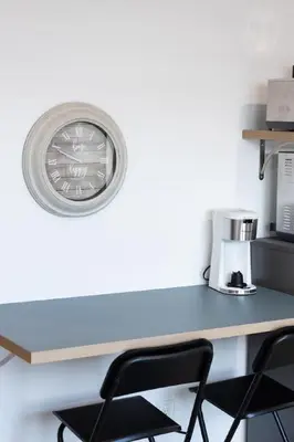 a clock on a wall above a desk with chairs at City excitement -Studio 20 Minutes to (42st) NYC in West New York