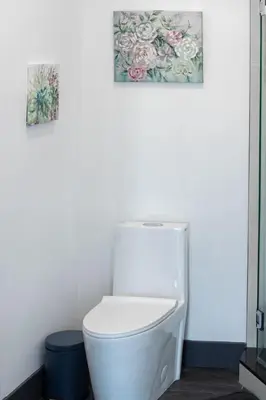 a white toilet in a bathroom with two pictures on the wall at Stylish Studio Apt-Outside NYC in West New York