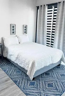 a bedroom with a large bed with a blue rug at Stylish Studio Apt-Outside NYC in West New York