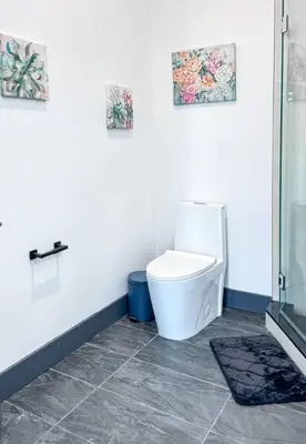 a bathroom with a toilet with two pictures on the wall at Stylish Studio Apt-Outside NYC in West New York