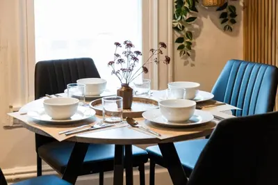 a wooden table with plates and utensils on it at Bright, Cozy, and Peaceful Two Bedroom Apt Near NYC in North Bergen