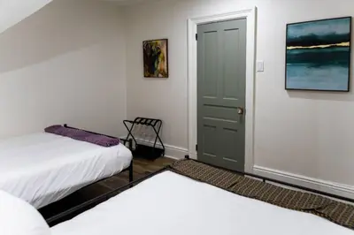 two beds in a room with a door and a chair at Bright, Cozy, and Peaceful Two Bedroom Apt Near NYC in North Bergen