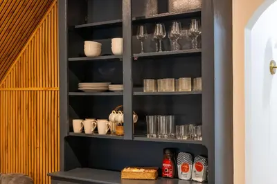 a black shelf with glasses and dishes on it at Bright, Cozy, and Peaceful Two Bedroom Apt Near NYC in North Bergen
