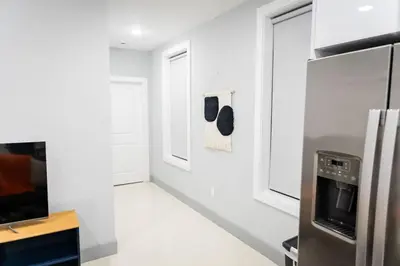 a kitchen with white walls and a stainless steel refrigerator at City Adventure-Quick NYC Access-2BR-Free Parking in West New York