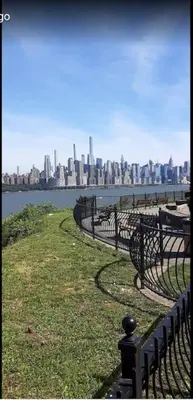 a row of park benches with a city in the background at Quick NYC Access with Free Parking Two Bedrooms Near NYC in West New York