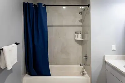 a bathroom with a shower with a blue shower curtain at Bright Apartment with Free Parking Near NYC in West New York