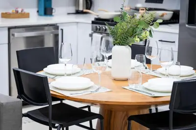 a wooden table with glasses and a vase of flowers at Bright Apartment with Free Parking Near NYC in West New York