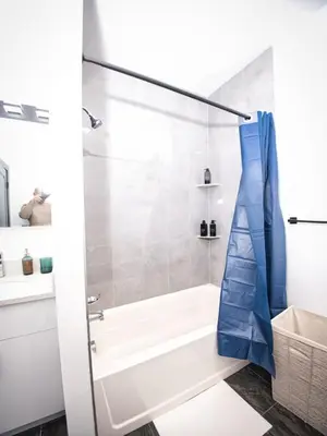 a white bathroom with a tub and a shower at Prime Location with Free Parking Near NYC in West New York