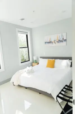 a white bedroom with a large bed and a window at Modern 1 Bedroom Apt with Quick NYC Access and Free Parking in West New York