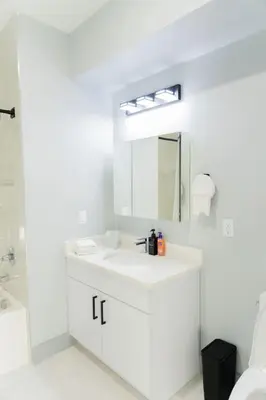 a white bathroom with a sink and a mirror at Modern 1 Bedroom Apt with Quick NYC Access and Free Parking in West New York