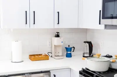 a kitchen counter with white cabinets and a coffee maker at Modern 1 Bedroom Apt with Quick NYC Access and Free Parking in West New York