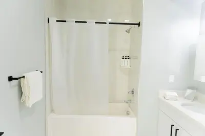 a white bathroom with a shower and a sink at Modern 1 Bedroom Apt with Quick NYC Access and Free Parking in West New York
