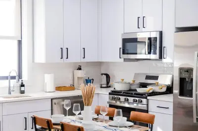 a kitchen with white cabinets and a table with chairs at Modern 1 Bedroom Apt with Quick NYC Access and Free Parking in West New York