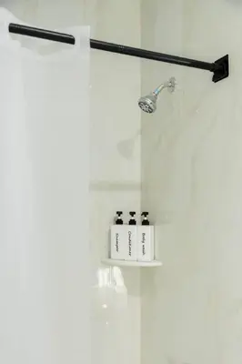 a shower with three bottles on a shelf in a bathroom at Modern 1 Bedroom Apt with Quick NYC Access and Free Parking in West New York