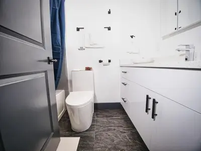 a white bathroom with a toilet and a sink at Explore New York City-20 Minutes Away With Parking in West New York