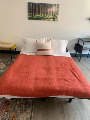a bed with a red blanket on top of it at Great Location-20 Mins to NYC-Free Indoor Parking in West New York