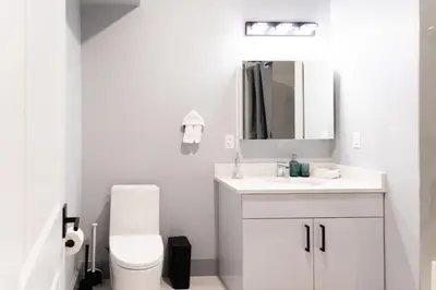 a white bathroom with a toilet and a sink at 2 Bedroom Apt-City Adventure-Free Parking on Site in West New York