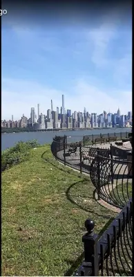 a row of park benches with a city in the background at 2 Bedroom Apt-City Adventure-Free Parking on Site in West New York