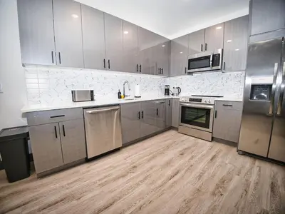 a large kitchen with stainless steel appliances and wooden floors at Free Indoor Parking 25 Minutes to NYC in West New York