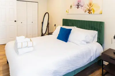 a bedroom with a white bed with a green headboard at Spacious 2-Bedroom Apartment NYC-10 mins away in Union City