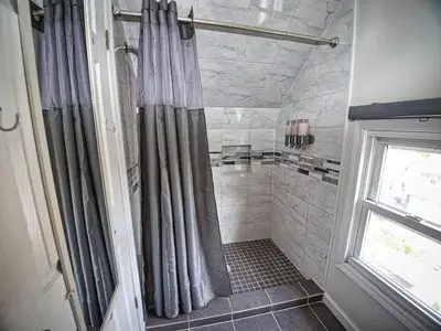 a shower with gray shower curtains in a bathroom at Comfy 3rd Floor Studio Near NYC in Ridgefield Park