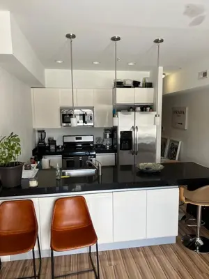 a kitchen with a black counter and orange chairs at Private Suite Hudson River View in Union City