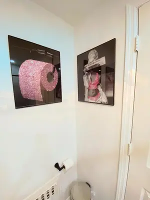 a bathroom with three pictures and a toilet paper dispenser at Private room B in West NYNJ 12mints from NYCity Times Square in West New York