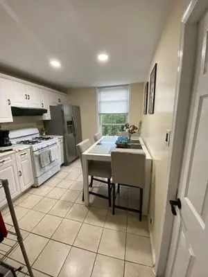 a kitchen with a table and a kitchen with white cabinets at Private room B in West NYNJ 12mints from NYCity Times Square in West New York