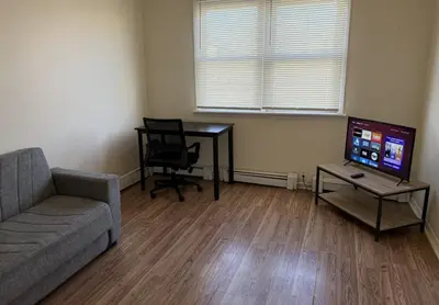 a living room with a couch and a table and a television at Private one-bedroom and one-bathroom apartment, private street entrance in convenient area, MetLife Stadium FIFA World Cup 35 minutes away in Perth Amboy