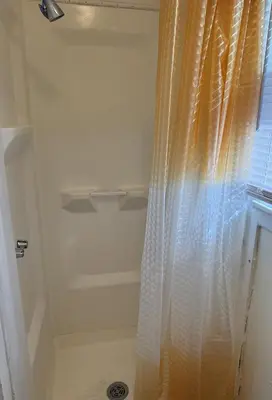 a shower with an orange curtain next to a window at Private one-bedroom and one-bathroom apartment, private street entrance in convenient area, MetLife Stadium FIFA World Cup 35 minutes away in Perth Amboy