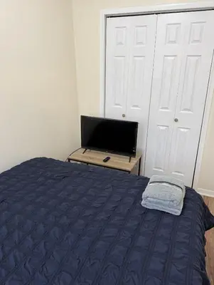 a bedroom with a bed and a flat screen tv at Private one-bedroom and one-bathroom apartment, private street entrance in convenient area, MetLife Stadium FIFA World Cup 35 minutes away in Perth Amboy
